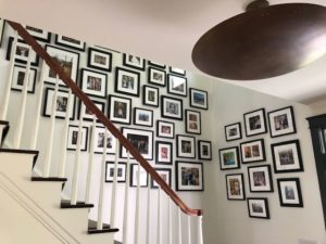 Many family photos in black and white frames on a staircase wall