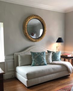 A round gold framed mirror over a divan installed by Ilevel