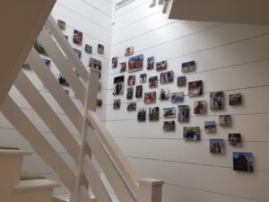 Many colorful, unframed snapshots hanging in an arrangement up a stairway