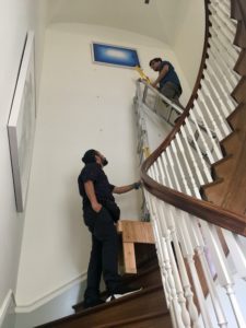 to show professional art installers hanging art on a staircase