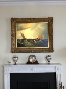 A beautiful painting hangs above a fireplace