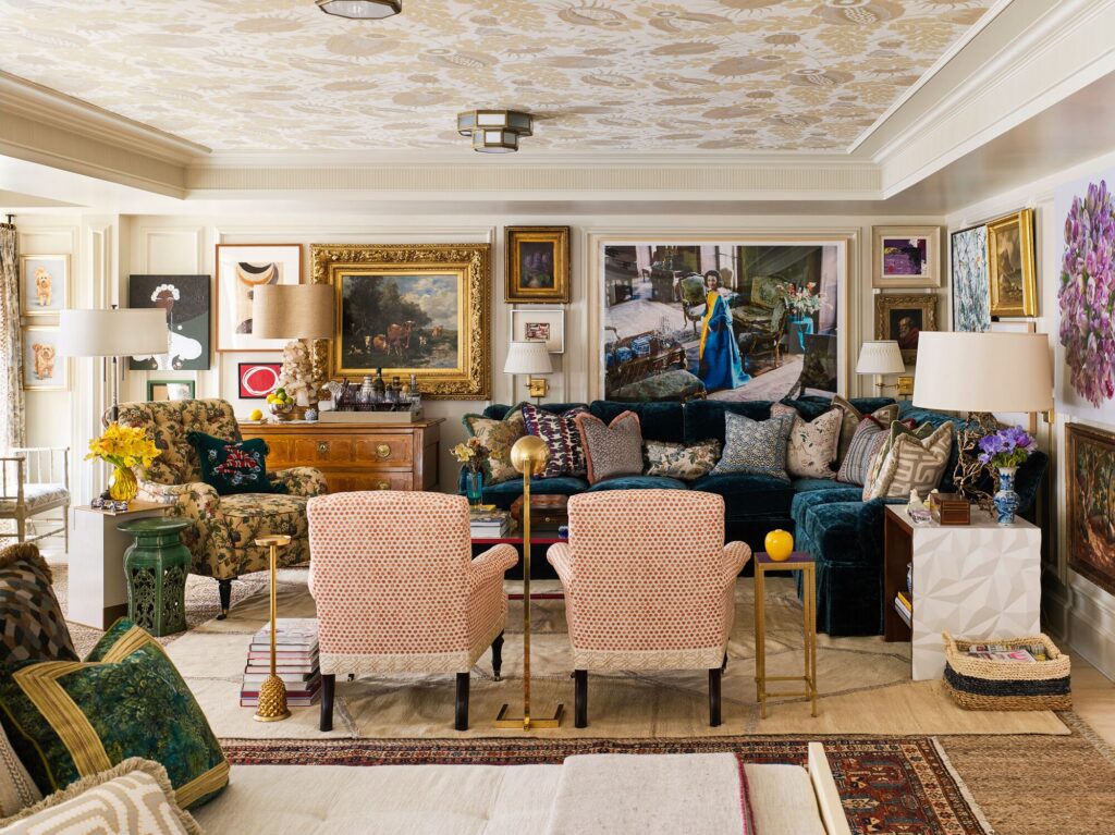 Decadent collection of art work hung in bright living room about blue couch