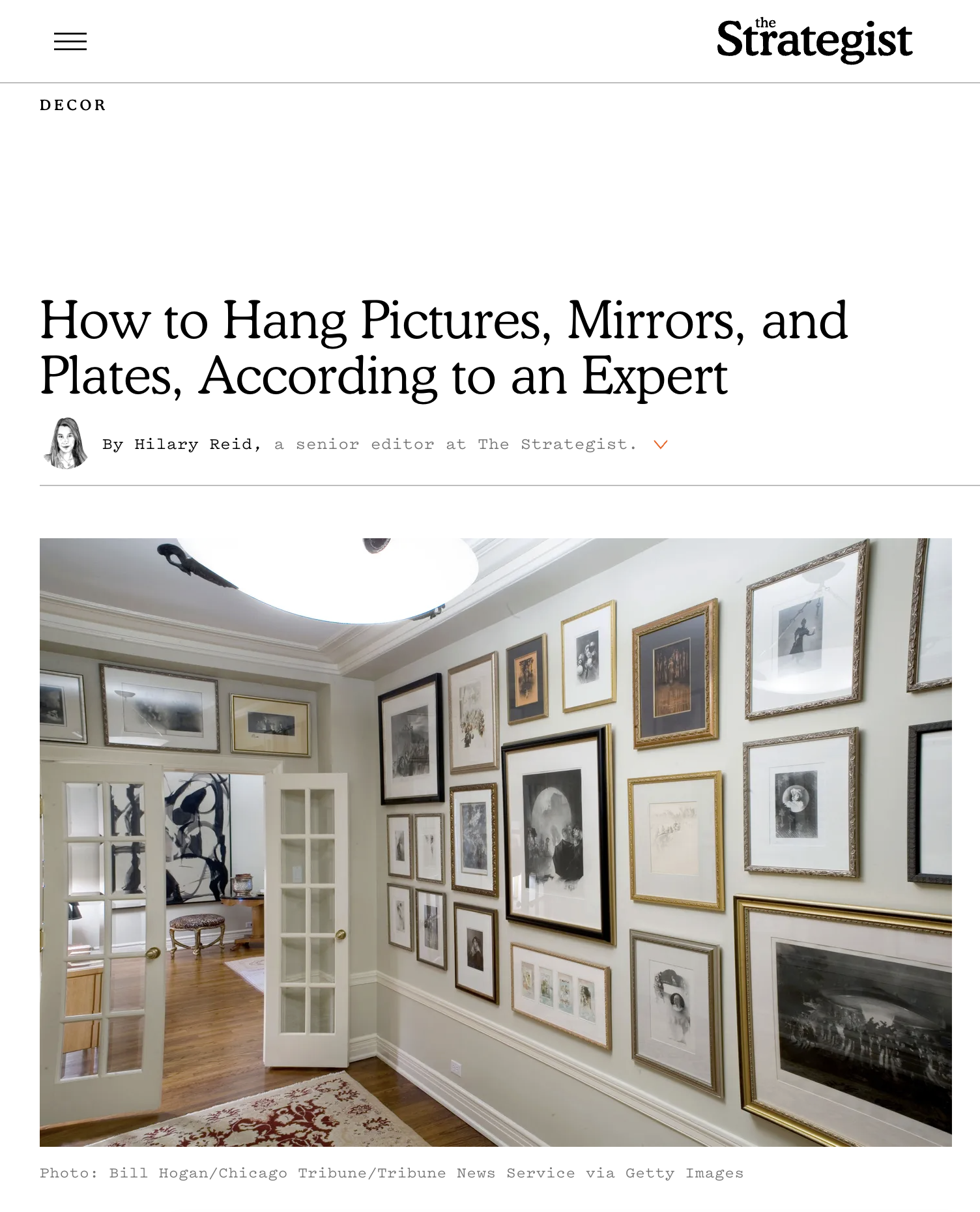 Screenshot of The Strategist Website, with headline "how to hang pictures, mirrors, and plates, according to an expert" the photo shows a long hallway covered in frames pictures