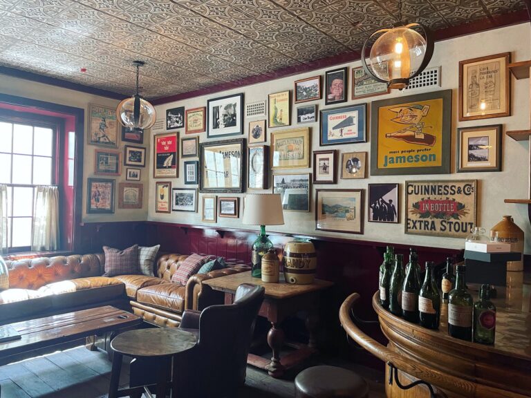 Rustic gallery wall above leather sofa, lots of diverse art hung on white wall