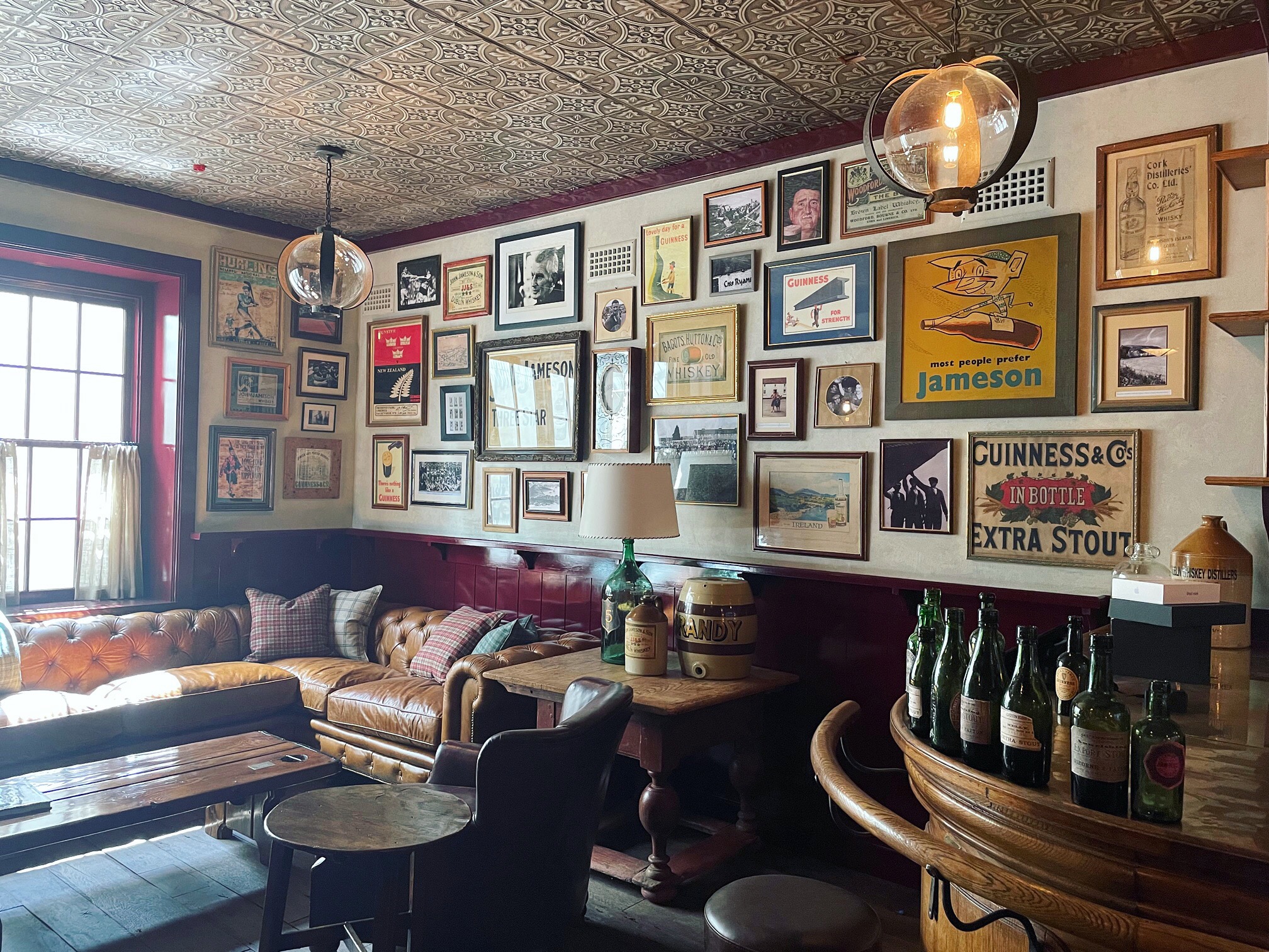 Rustic gallery wall above leather sofa, lots of diverse art hung on white wall