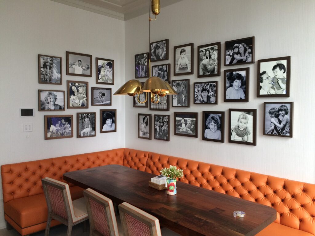 two walls adorned with large gallery wall installation, hung above orange bench and kitchen nook