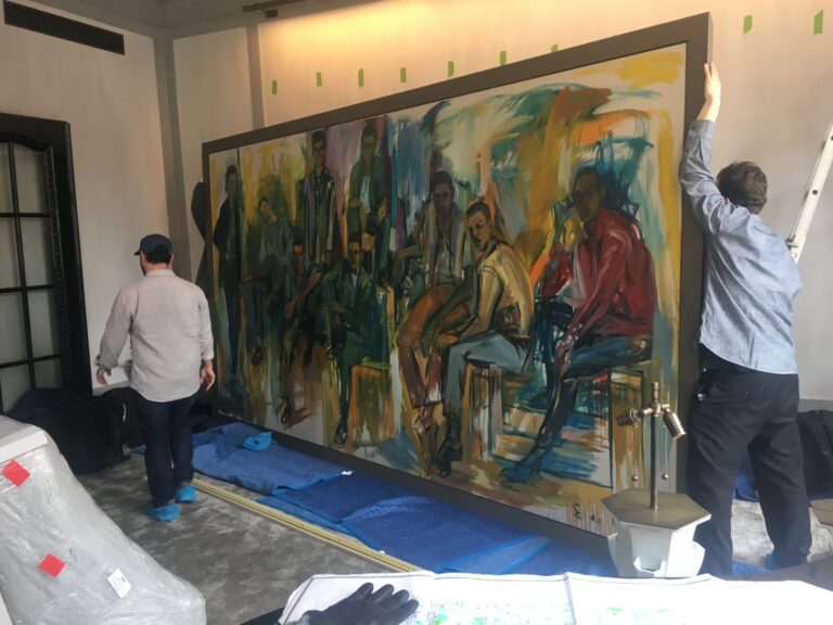 Two art handlers installing large scale piece of art on wall