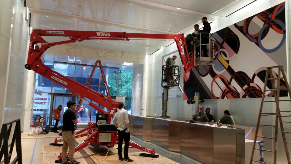 Large crane used indoors to hang oversized art on lobby wall