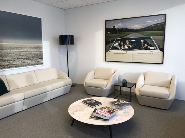Photo of large art installed behind two white chairs in corporate office