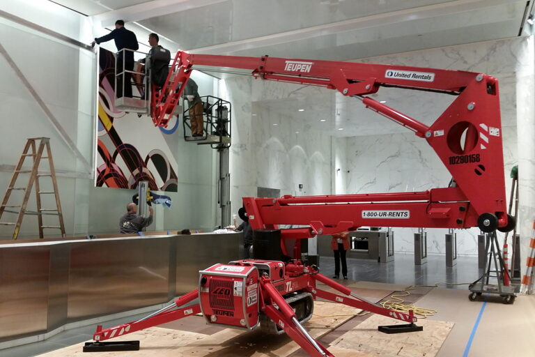 ILevel installers mounting a large artwork in a commercial lobby still under construction