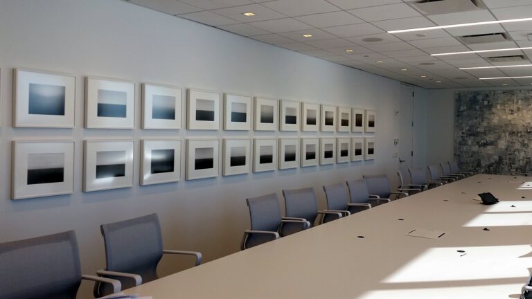 Long office corridor lined on both sides with two rows of evenly spaced framed works