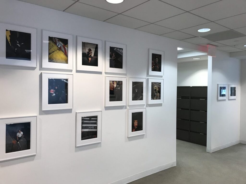Salon-style photography wall installed along an office corridor.