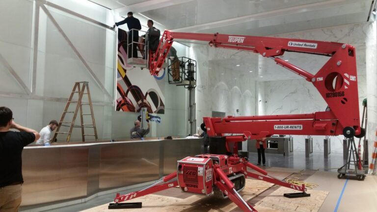ILevel installers using a lift to mount a large artwork in a marble office lobby.