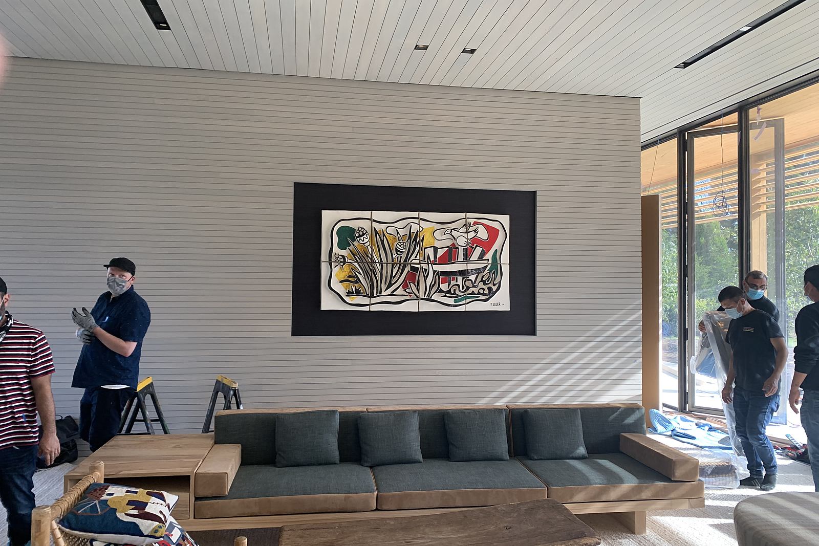 ILevel art installers beside a newly installed tapestry above a lounge sofa
