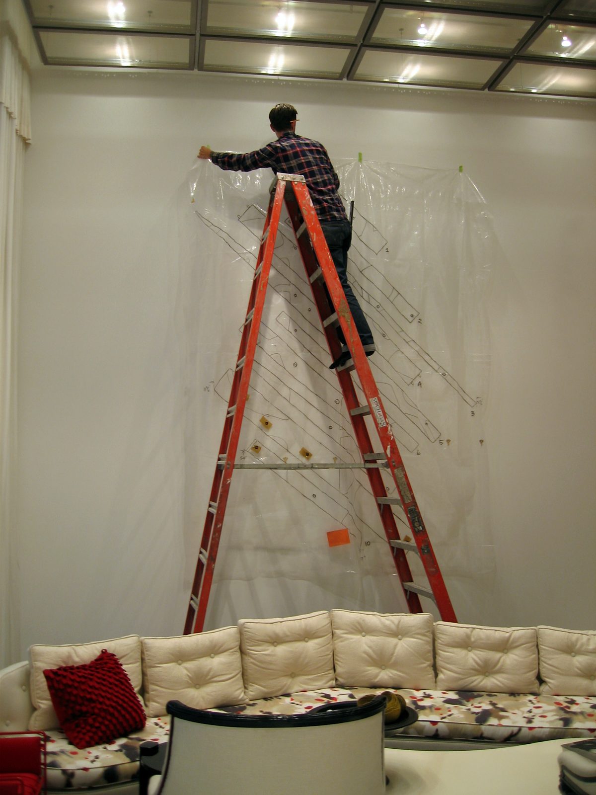 ILevel installer on a ladder taping a full-size paper template to the wall before installation