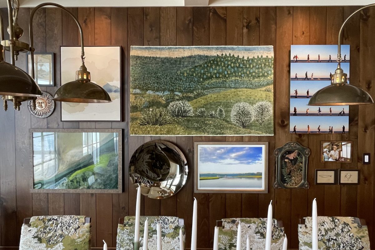 Gallery wall installation in a dining room with wood-paneled walls, featuring paintings, photography, a tapestry, and a mirror arranged by ILevel