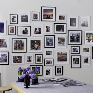 family photo wall hung above grey kitchen table. photos are a mix of family members, beautiful locations and cherised memories