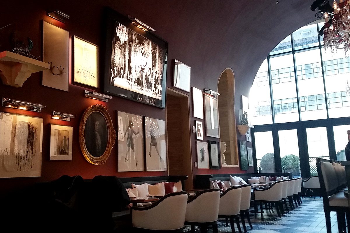 Image of large wall alongside several restaurant tables, with big window overlooking manhattan