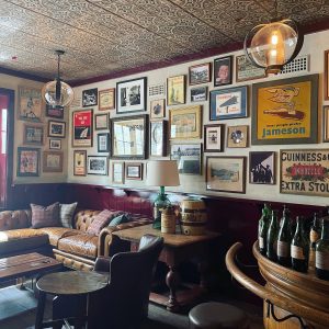 Rustic gallery wall above leather sofa, lots of diverse art hung on white wall